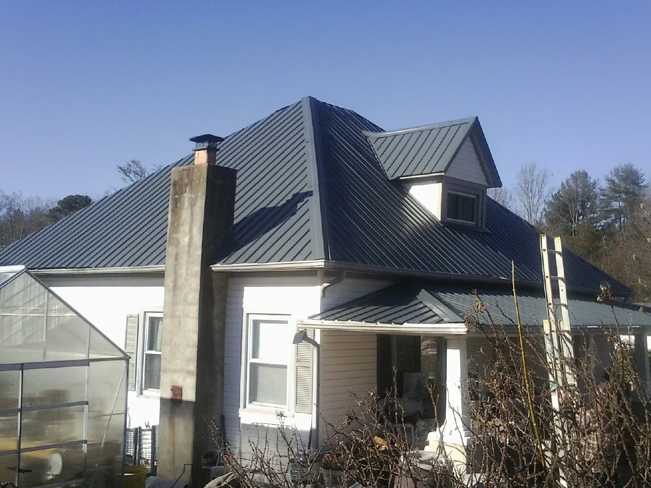 Dark blue standing seam metal roof on a white farmhouse with dormer — Slate & Tile Roof Repair by Roofing Brothers in Dukedom