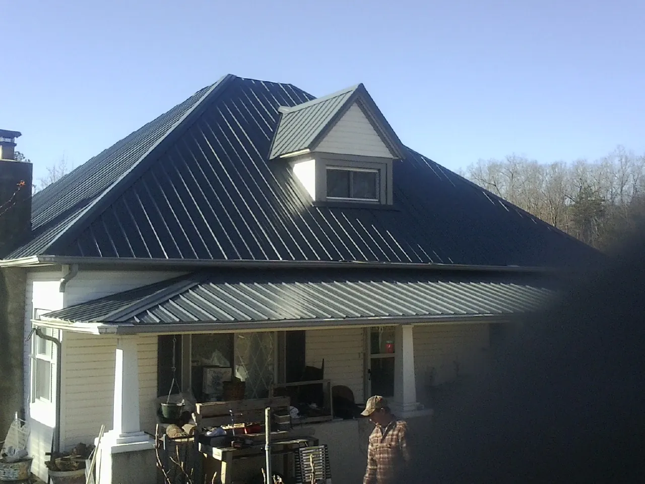 Dark blue standing seam metal roof with a dormer above a front porch in Dukedom