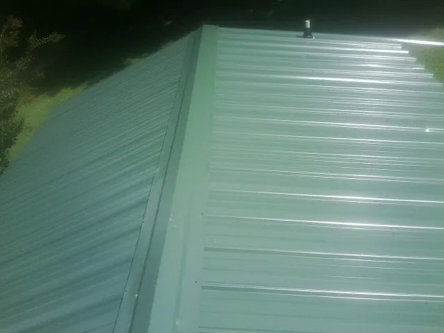 New green metal panels meeting at the ridge of a roof — Flat Roof Repair work by our crew in Dukedom
