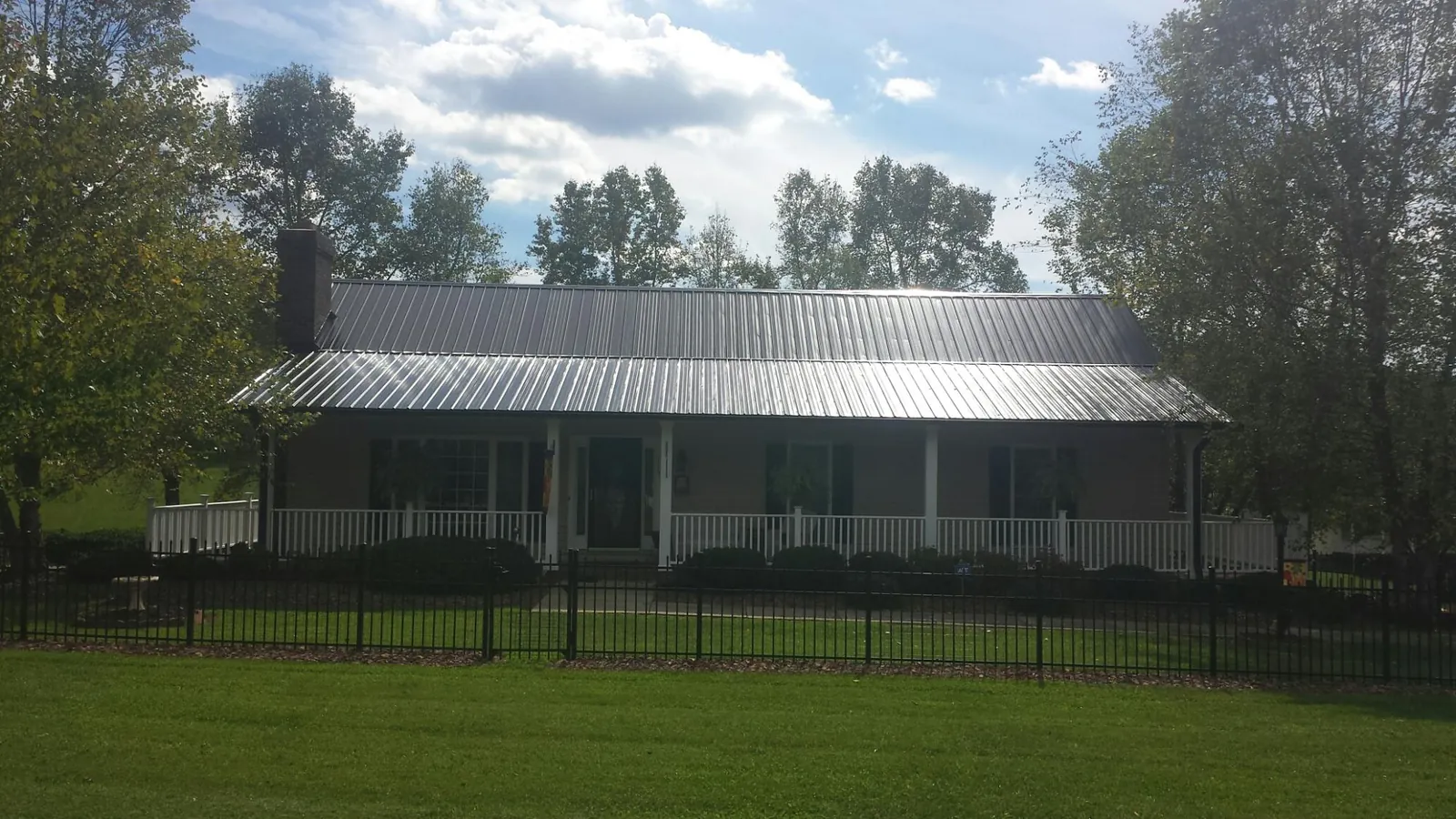 Gray metal roof on a brick ranch with a full width front porch — Gutter Guard Installation work by our crew in Dukedom