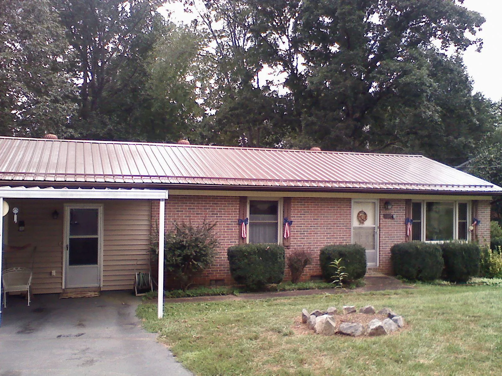 Bronze metal roof and carport on a brick ranch home — Roof Repair work by our crew in Dukedom