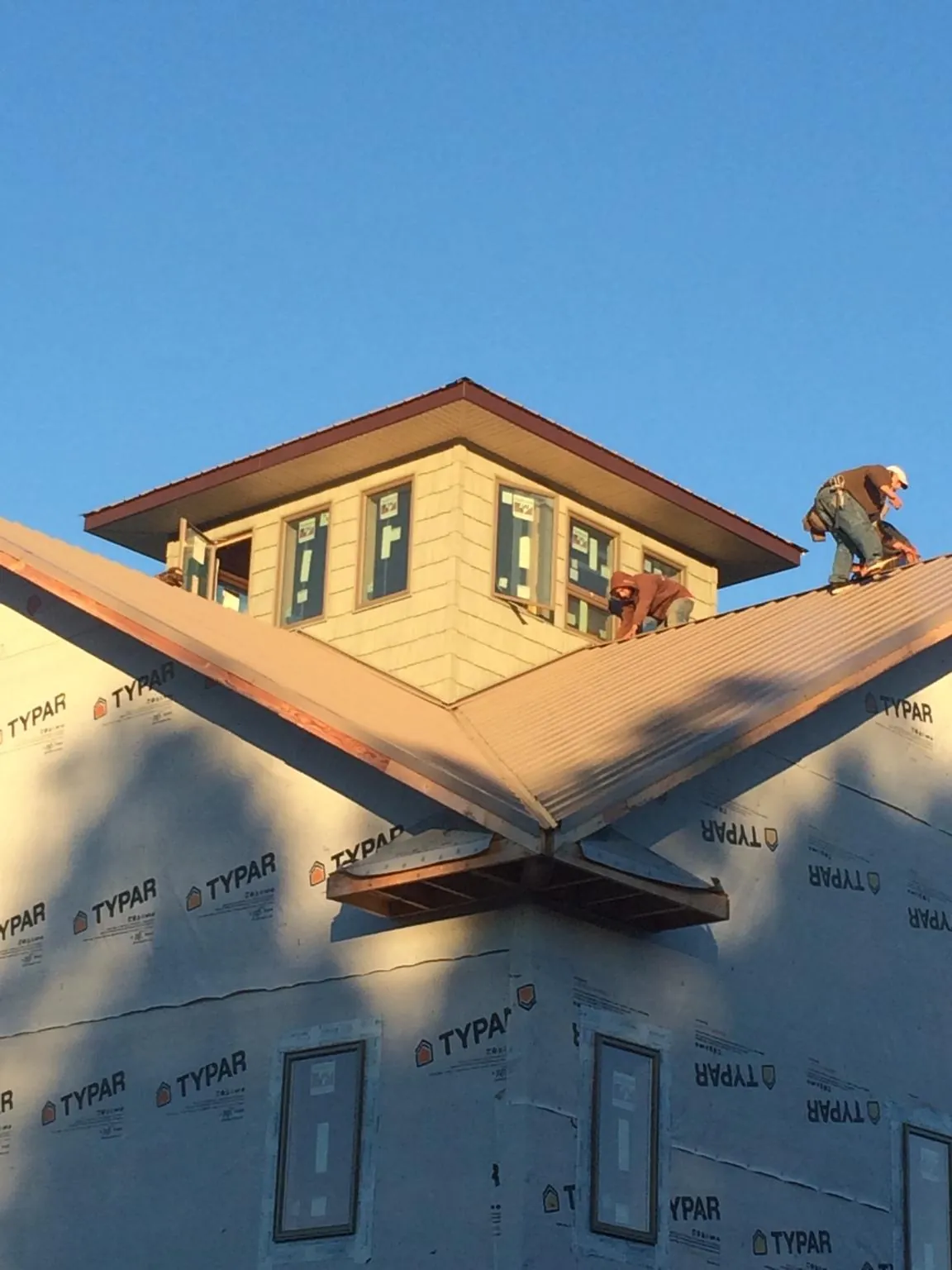 Roofers working around a rooftop cupola on a new metal roof at sunset — Roof Waterproofing in Dukedom by Roofing Brothers